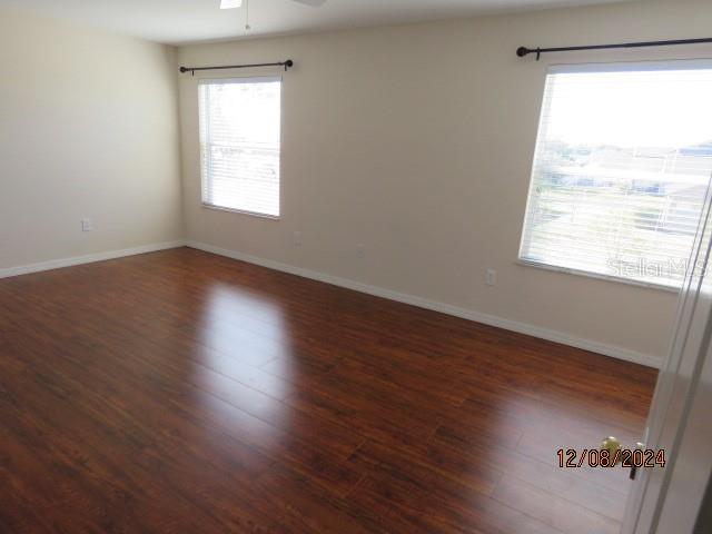 empty room with dark hardwood / wood-style flooring and ceiling fan