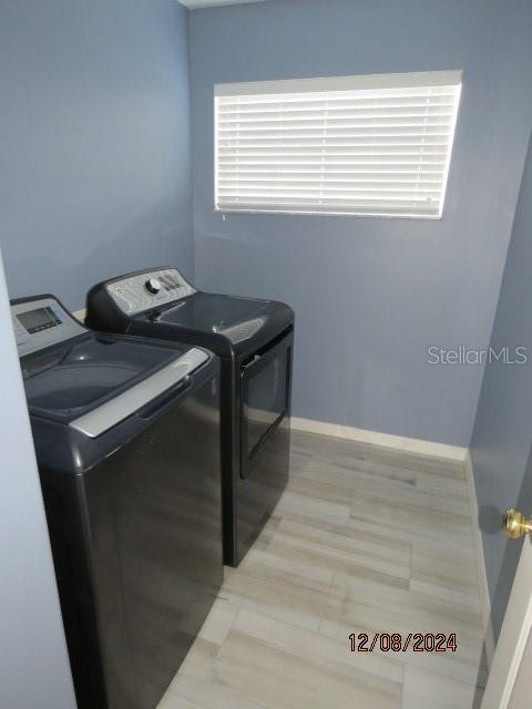 laundry room with separate washer and dryer and light hardwood / wood-style flooring