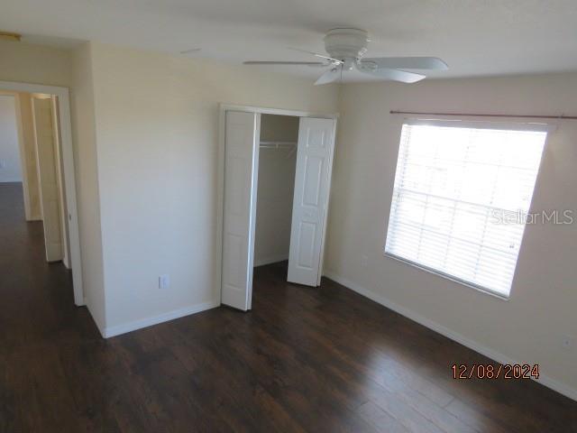 unfurnished bedroom with dark hardwood / wood-style flooring, a closet, and ceiling fan