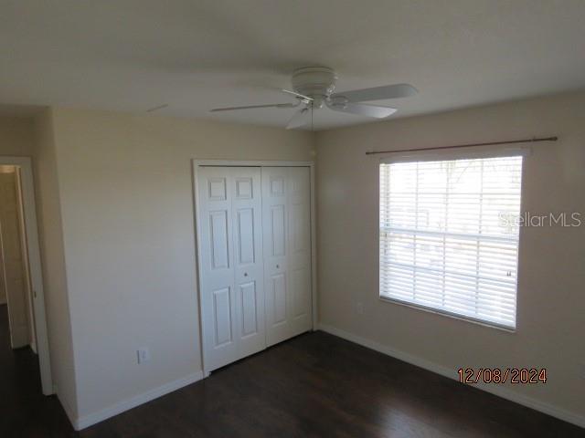 unfurnished bedroom with dark hardwood / wood-style flooring, a closet, and ceiling fan