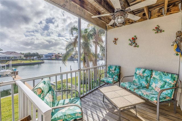 sunroom featuring ceiling fan and a water view