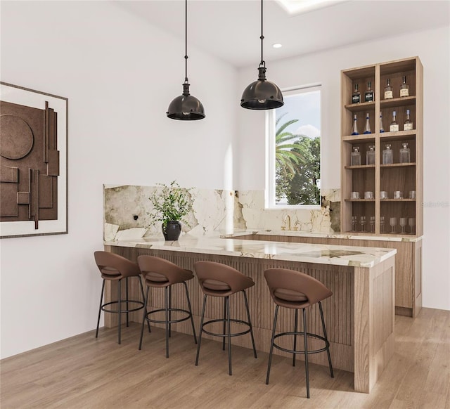 bar featuring tasteful backsplash, light hardwood / wood-style flooring, and pendant lighting