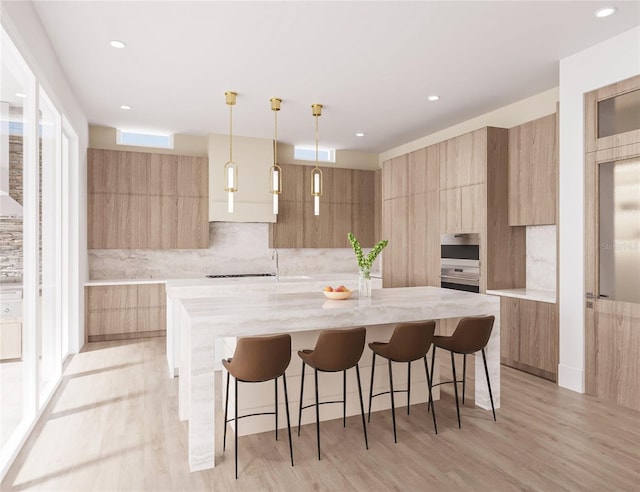 kitchen featuring light hardwood / wood-style flooring, hanging light fixtures, a large island, and light stone counters