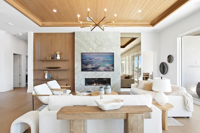 living room with a premium fireplace, wood ceiling, a raised ceiling, and light wood-type flooring