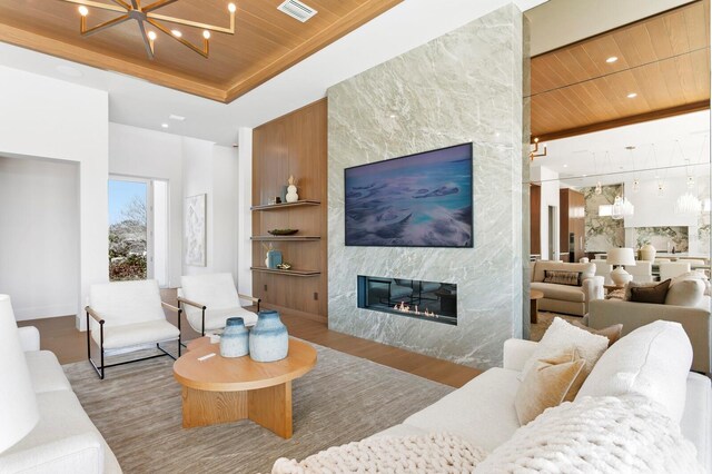 living room with light wood-type flooring, a notable chandelier, wood ceiling, and a fireplace