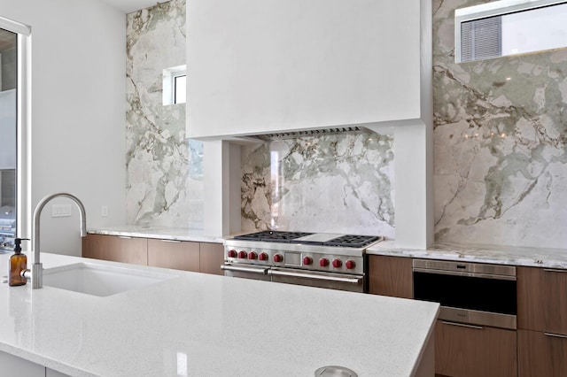 kitchen featuring sink, decorative backsplash, stainless steel appliances, and light stone countertops