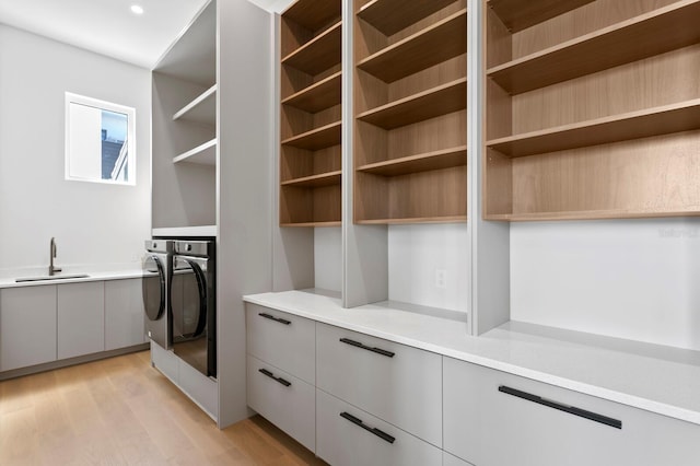 interior space featuring separate washer and dryer, sink, and light hardwood / wood-style flooring