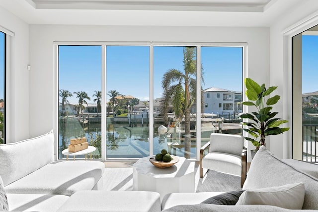 sunroom / solarium featuring a water view and a tray ceiling