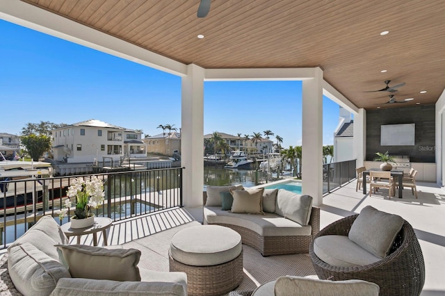 view of patio with a balcony, outdoor lounge area, ceiling fan, and a water view