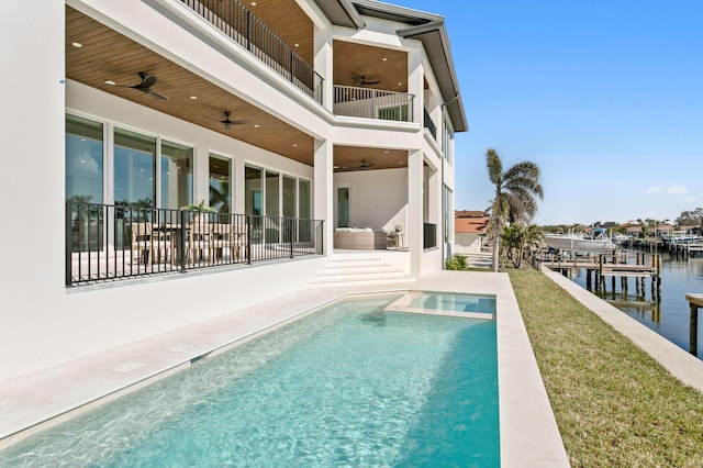 view of pool with a patio, ceiling fan, and a water view