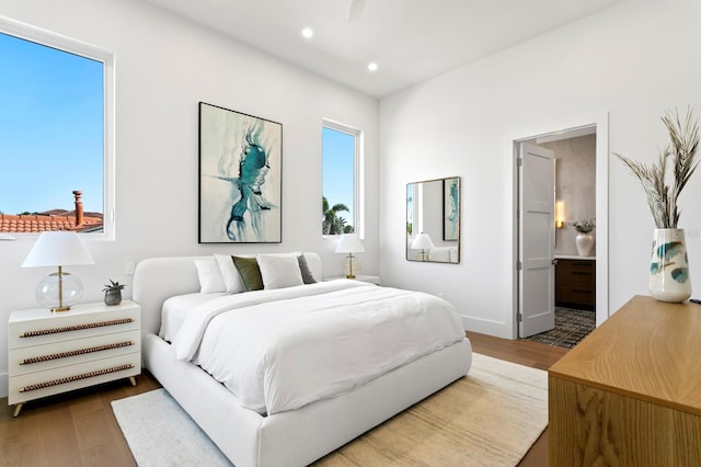 bedroom featuring ensuite bath, hardwood / wood-style floors, and multiple windows