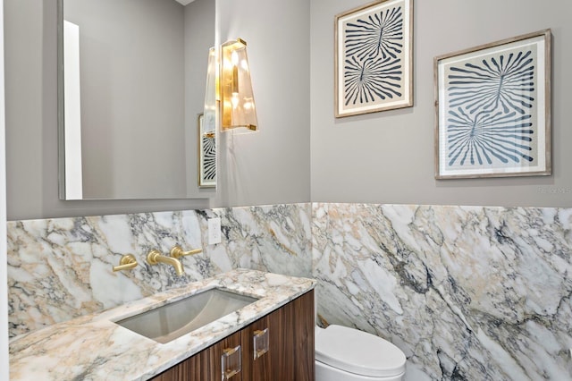 bathroom with vanity, tile walls, and toilet