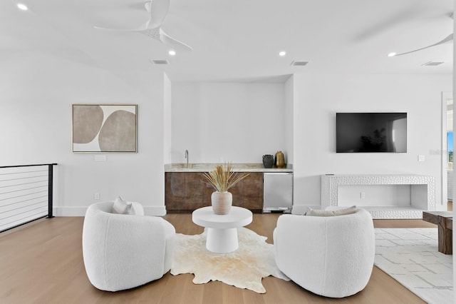 living room with wood-type flooring, wet bar, and ceiling fan