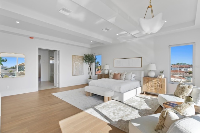 bedroom with a raised ceiling, light hardwood / wood-style floors, and multiple windows