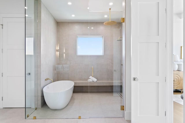 bathroom with plus walk in shower, tile patterned flooring, and tile walls