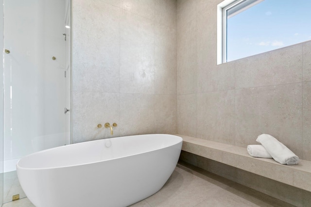 bathroom featuring a bathing tub, tile walls, and tile patterned floors