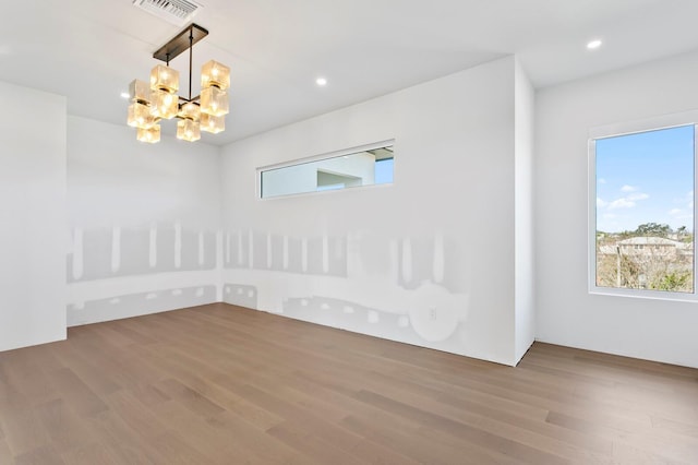 unfurnished room featuring hardwood / wood-style floors and an inviting chandelier