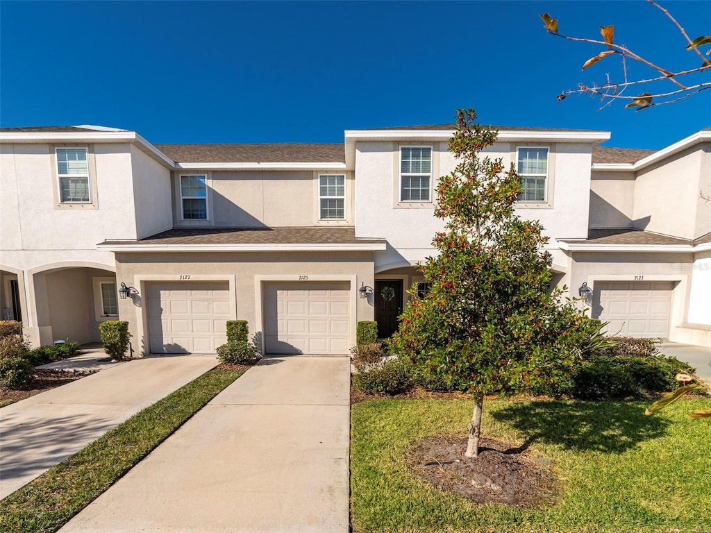 townhome / multi-family property with a front yard and a garage