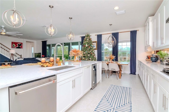 kitchen with stainless steel dishwasher, a chandelier, sink, and white cabinets