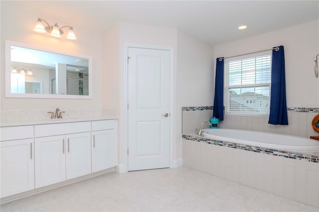 bathroom with vanity and tiled tub