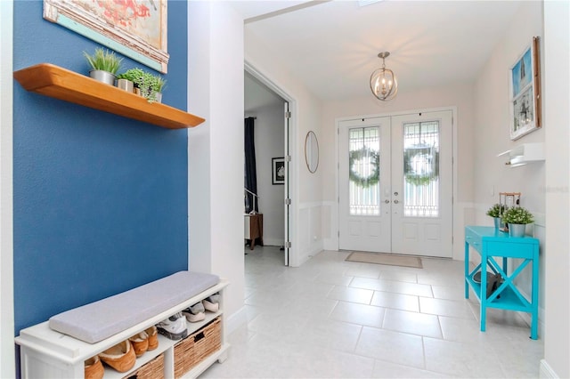 tiled foyer featuring an inviting chandelier and french doors