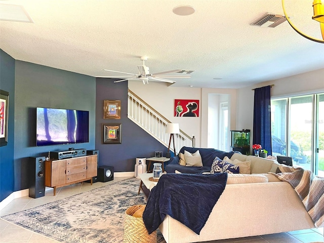 living area featuring baseboards, visible vents, stairs, a textured ceiling, and tile patterned floors