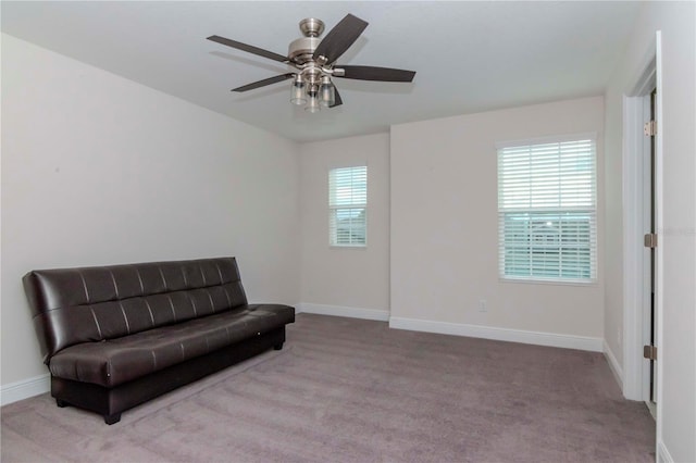 living area with baseboards, carpet floors, and a ceiling fan