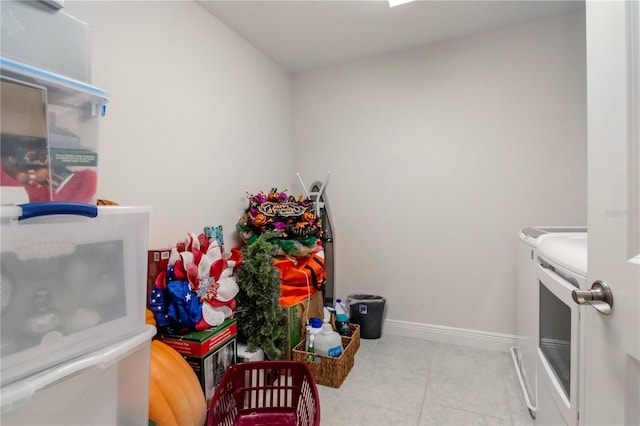 clothes washing area with washer and clothes dryer, laundry area, tile patterned flooring, and baseboards