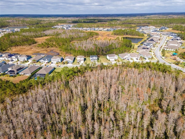 drone / aerial view featuring a residential view, a wooded view, and a water view