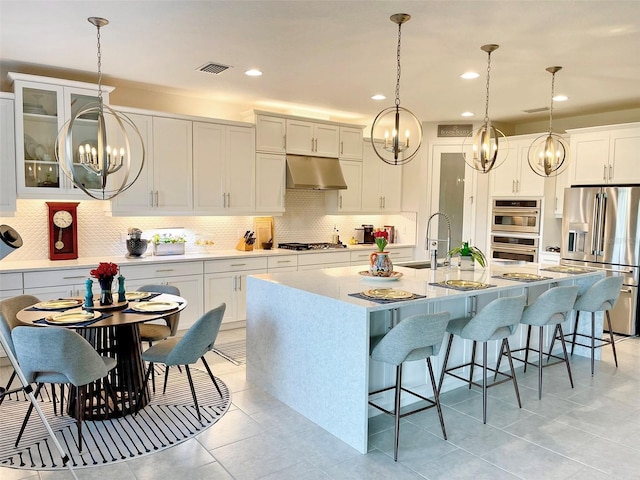 kitchen with visible vents, under cabinet range hood, a sink, tasteful backsplash, and stainless steel appliances