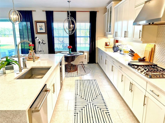 kitchen with an inviting chandelier, appliances with stainless steel finishes, extractor fan, and a sink