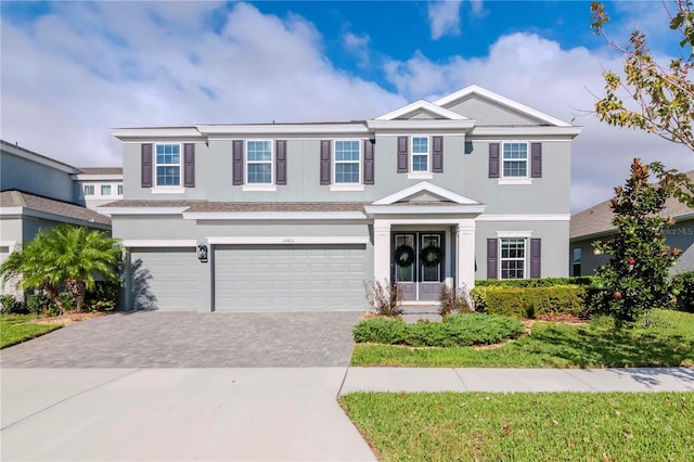 view of front of house with stucco siding, decorative driveway, a garage, and french doors