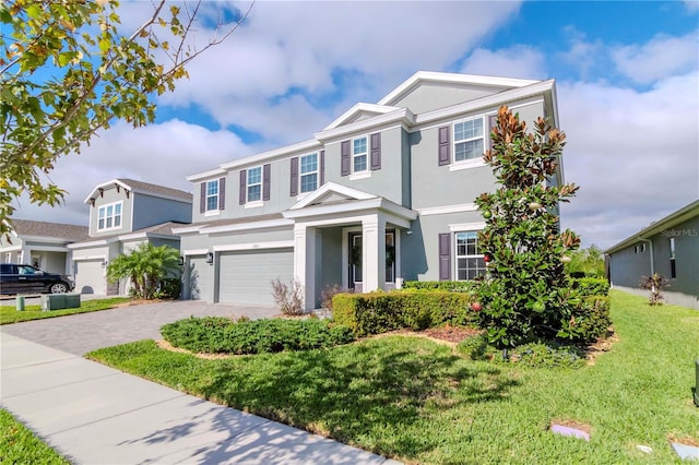 view of front of property featuring stucco siding, an attached garage, decorative driveway, and a front yard