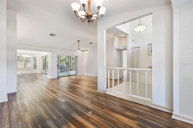 spare room with ceiling fan with notable chandelier, dark hardwood / wood-style flooring, and vaulted ceiling