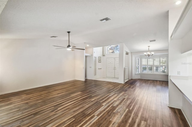 unfurnished living room with a textured ceiling, ceiling fan with notable chandelier, vaulted ceiling, and dark wood-type flooring