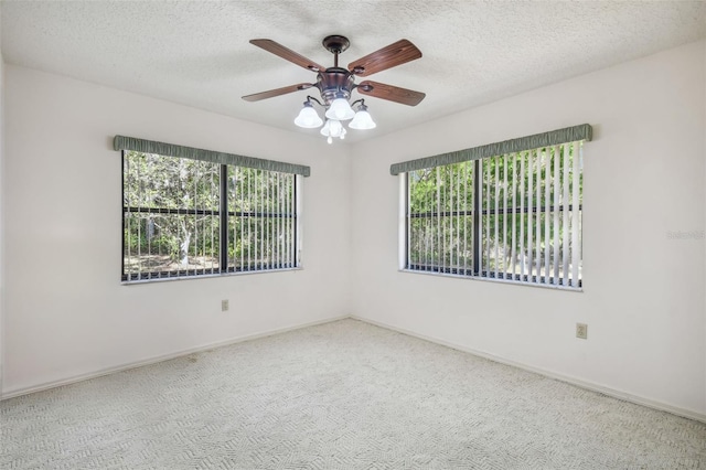 empty room featuring carpet flooring, ceiling fan, a healthy amount of sunlight, and a textured ceiling