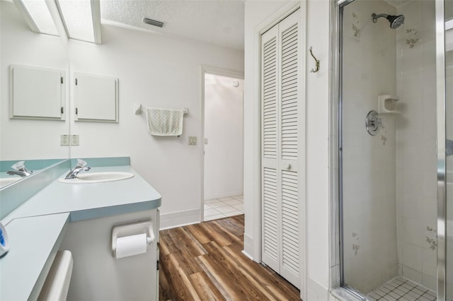 bathroom with a textured ceiling, vanity, hardwood / wood-style flooring, and a shower with shower door