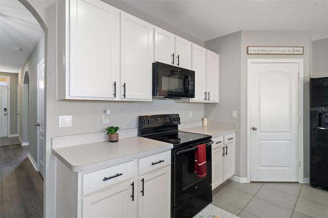 kitchen with light wood-type flooring, white cabinetry, and black appliances