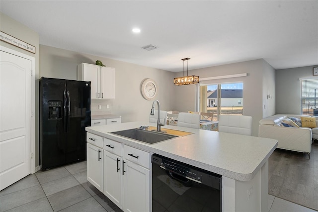 kitchen with white cabinets, an island with sink, a wealth of natural light, and black appliances