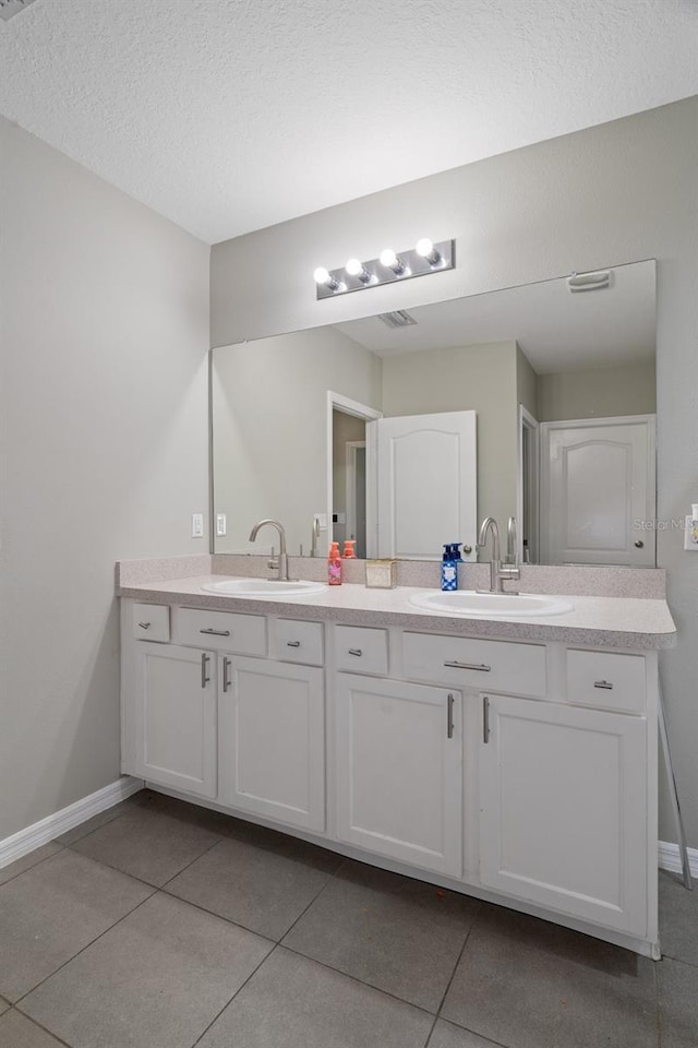 bathroom with tile patterned floors, vanity, and a textured ceiling