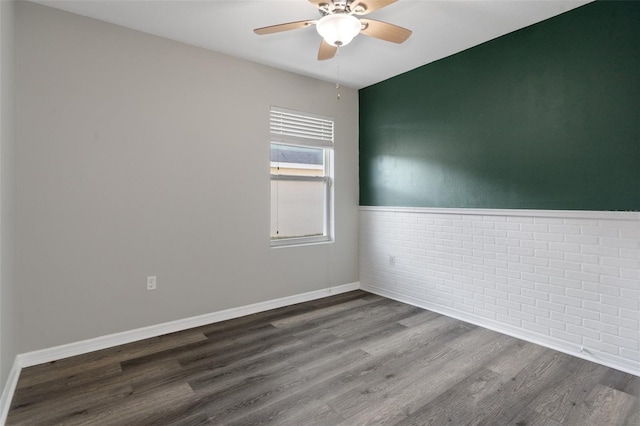 unfurnished room with wood-type flooring, ceiling fan, and brick wall