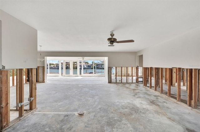 interior space featuring ceiling fan, a water view, and concrete floors