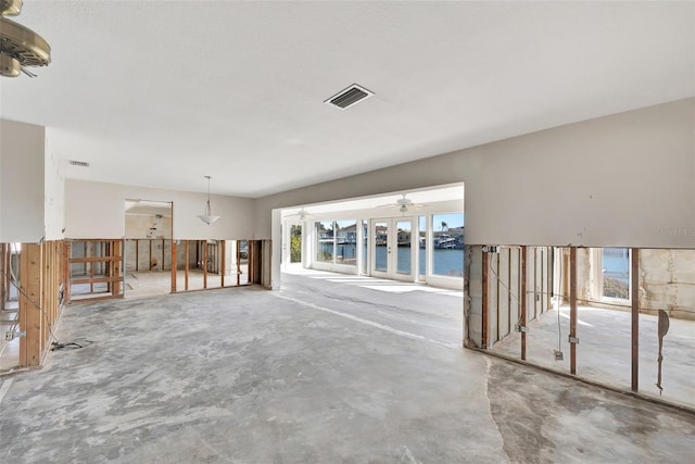 unfurnished living room with concrete floors, a water view, and ceiling fan