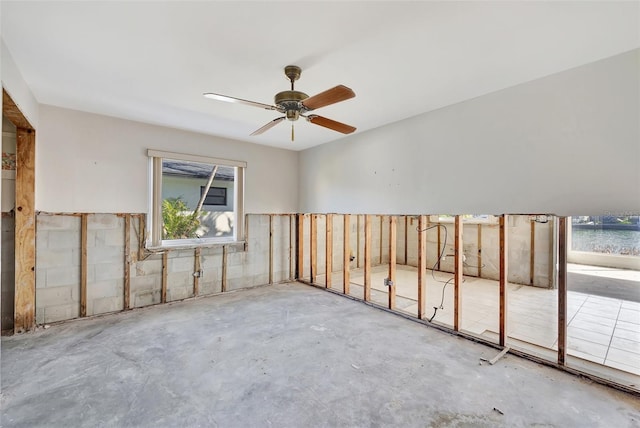 empty room with ceiling fan, a water view, and concrete floors