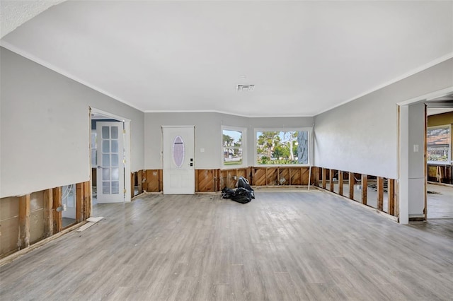 interior space featuring light hardwood / wood-style floors, crown molding, and wooden walls