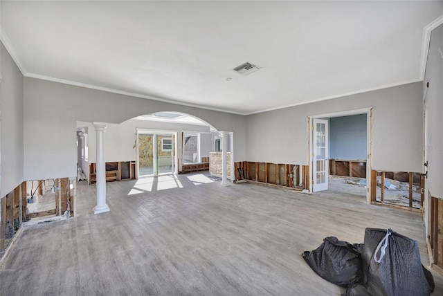 living room featuring wood walls, french doors, light wood-type flooring, ornate columns, and ornamental molding