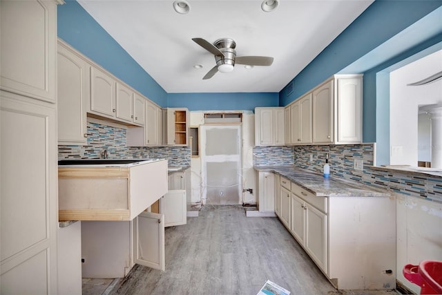 kitchen with light stone countertops, light hardwood / wood-style floors, tasteful backsplash, and ceiling fan