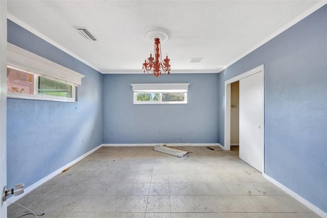 spare room with a notable chandelier, ornamental molding, and a wealth of natural light