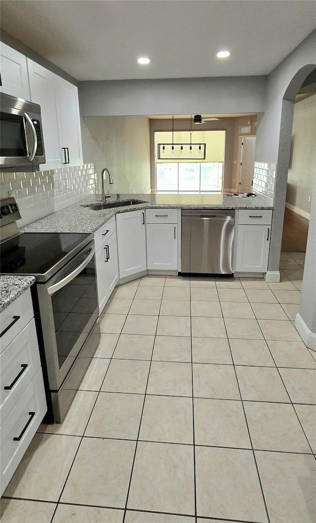 kitchen with white cabinets, appliances with stainless steel finishes, decorative light fixtures, sink, and light tile patterned flooring