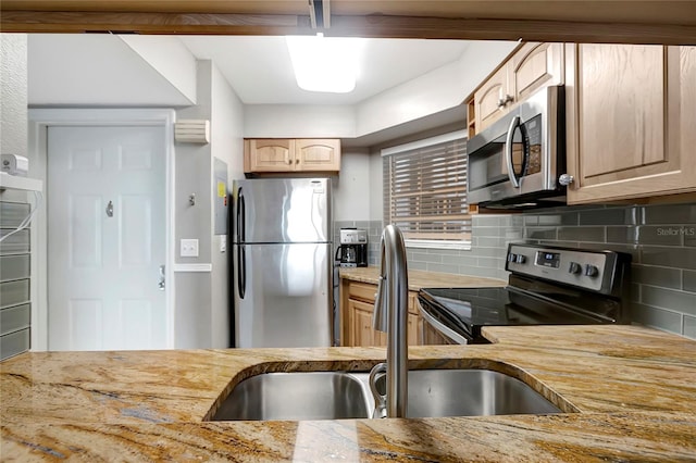 kitchen with light stone countertops, sink, light brown cabinets, tasteful backsplash, and appliances with stainless steel finishes